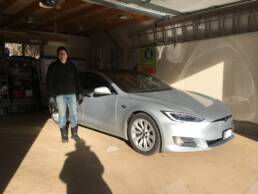 Jukka is standing next to his silver Tesla Model S, parked in his garage.