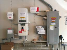 Jukka Kukkonen’s garage wall has a variety of electrical equipment to manage the energy flow of solar panels, storage batteries, and chargers. Everything was well-marked to show visitors.